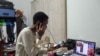FILE - Illustrator Sena Ahadji speaks to a client on the phone from her house in Accra, Ghana, July 24, 2015. 