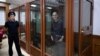 US journalist Evan Gershkovich, accused of espionage, smiles from inside a glass defendants' cage prior to a hearing in Yekaterinburg's Sverdlovsk Regional Court on June 26, 2024. (Photo by NATALIA KOLESNIKOVA / AFP)