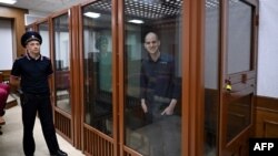 US journalist Evan Gershkovich, accused of espionage, smiles from inside a glass defendants' cage prior to a hearing in Yekaterinburg's Sverdlovsk Regional Court on June 26, 2024. (Photo by NATALIA KOLESNIKOVA / AFP)