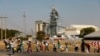 FILE - Members of the mining community carry donated food parcels at the Khomanani mine in Rustenburg, South Africa, May 2014. 