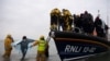 Para migran tampak dibantu oleh anggota Institut Nasional Kapal Penyelat Inggris (RNLI) setelah tiba di Dungeness, di bagian pesisir tenggara Inggris, pada 24 November 2021. Para migran itu diselamatkan dalam perjalanan mereka melewati Selat Inggris. (Foto: AFP/Ben Stansall)