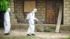 A healthcare worker in protective gear sprays disinfectant around the house of a person suspected to have Ebola virus in Port Loko Community, situated on the outskirts of Freetown, Sierra Leone, Oct. 21, 2014. 