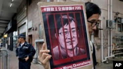 FILE - A protester holds a picture of imprisoned and prominent Chinese human rights lawyer Wang Quanzhang during a protest outside the Chinese liaison office in Hong Kong on July 13, 2018.