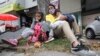 Venezuelan migrant Katerine Valero, 29, and her children Dariusca, 8, left, and Wilkerson, 4, rest outside a strip mall in Bogota, Colombia, Feb. 9, 2021.