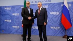 FILE - Russian President Vladimir Putin, right, and Iranian President Masoud Pezeshkian shake hands during their meeting on the sidelines of BRICS summit in Kazan, Russia, Oct. 23, 2024.