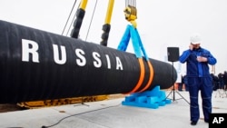 FILE - A Russian construction worker is seen next to a section of a natural gas pipeline.