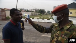 Un soldat vérifie la température corporelle d'un visiteur à l'hôpital de référence de l'armée nigériane à Yaba, à Lagos, le 28 février 2020. (AFP)