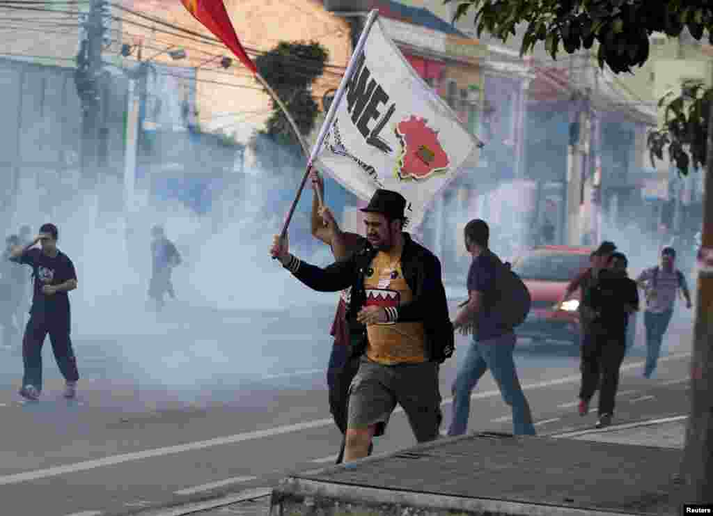 Demonstrators run from tear gas fired by police outside Ana Rosa subway station during the fifth day of metro workers' strike in Sao Paulo, Brazil, June 9, 2014.
