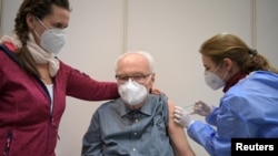 Werner Boestfleisch, 86, receives the first of two injections with a dose of the Pfizer-BioNTech COVID-19 vaccine from doctor Conny Mauruschat at the Metropolis-Halle vaccination center
