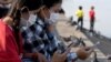 FILE - This photo taken on February 4, 2022, shows students using their smartphones while seated along the riverside in Phnom Penh.