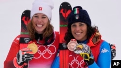 Michelle Gisin of Switzerland, gold, left, and Federica Brignone of Italy, bronze, celebrate after the medal ceremony for the women's combined at the 2022 Winter Olympics, Feb. 17, 2022, in the Yanqing district of Beijing.