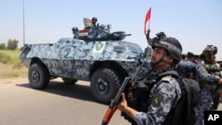 FILE - Iraqi federal policemen are seen patrolling Baghdad's Abu Ghraib suburb June 28, 2014.