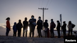 Migranti iz Srednje Amerike koji traže azil čekaju prevoz nakon što u Penitasu u Teksasu prešli rijeku Rio Grande.
