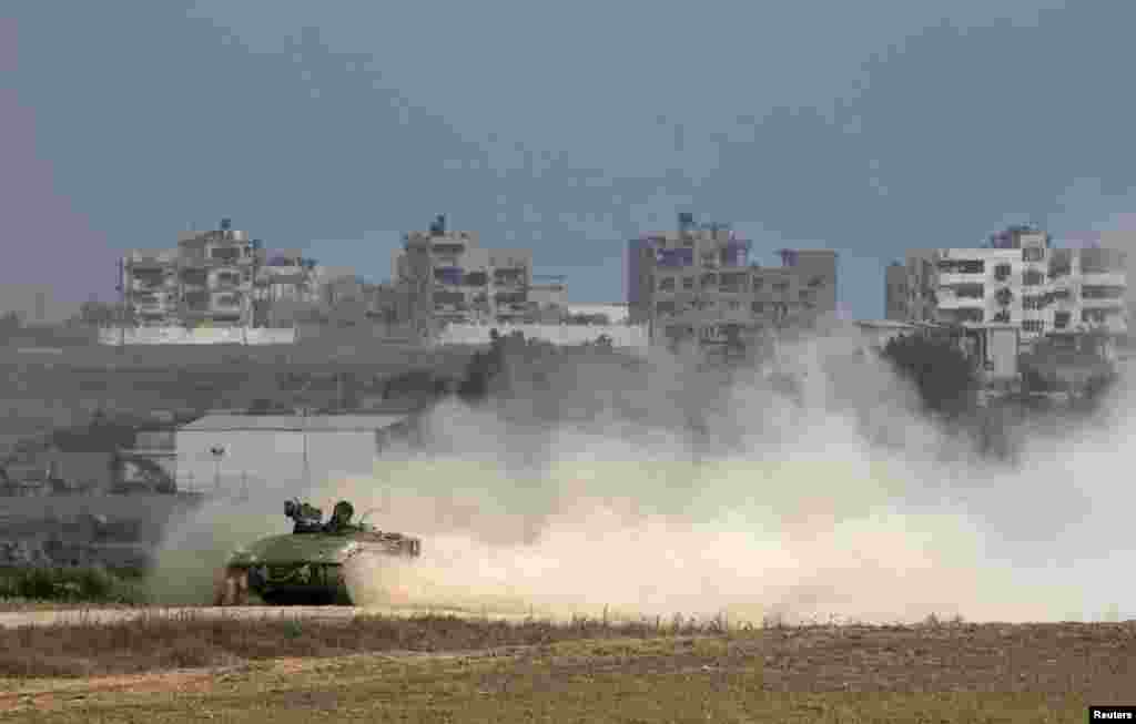 An Israeli armored personnel carrier (APC) drives back into Israel after crossing the northern Gaza Strip border (seen in background), July 28, 2014.