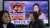 People pass a TV screen showing a news report on Sony Picture's 'The Interview,' at the Seoul Railway Station in South Korea.