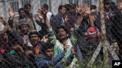 FILE - Migrants, most of them from Pakistan, protest the EU-Turkey migration deal inside the entrance of Moria camp in the Greek island of Lesbos, April 5, 2016. 