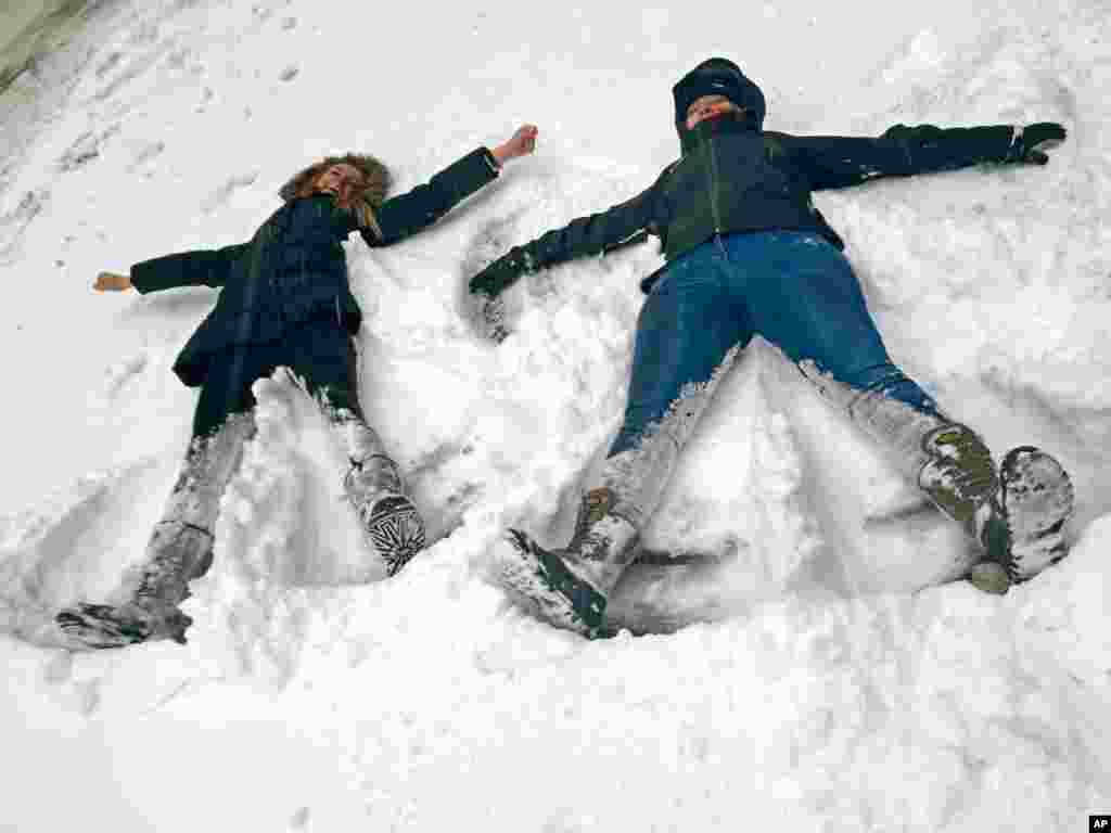 Bianca Hillier, left, of Columbus, Ohio, and Eloise Pollard of London take advantage of a snowtorm travel ban to do something they never envisioned: making snow angels on a normally busy stretch of Manhattan&rsquo;s Tenth Avenue at West 34th Street in New York, Jan. 27, 2015.