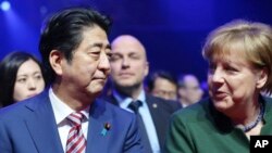 Le Premier ministre du Japon Shinzo Abe est assis aux côtés de la Chancelière allemande Angela Merkel, à l'ouverture du salon CeBIT à Hanovre, en Allemagne, le 19 mars 2017.