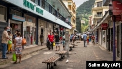 Des piétons portent des masques lorsqu'ils marchent dans une rue de la capitale Victoria, île de Mahé, Seychelles le 25 février 2021.