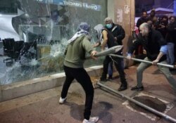 FILE - Anti-government protesters smash a bank widow, during ongoing protests against the Lebanese central bank's governor and against the deepening financial crisis, at Hamra trade street, in Beirut, Lebanon, Jan. 14, 2020.