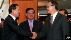 Cambodian Prime Minister Hun Sen, left, shakes hands with opposition party leader Sam Rainsy, right, after a meeting, as Sar Kheng, center, deputy prime minister, looks on at the National Assembly in Phnom Penh, Cambodia, Monday, Sept. 16, 2013. Hun Sen and Sam Rainsy met for the second time on Monday in a bid to resolve a political stalemate, a day after violent clashes on the streets of Phnom Penh. (AP Photo/Heng Sinith)