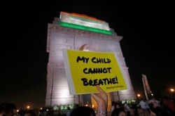A protestor holds a placard in front of the India Gate during a protest demanding the government take immediate steps to control air pollution in New Delhi, India, Nov. 5, 2019.