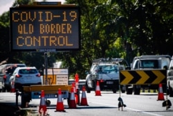 A COVID-19 signage is seen at a vehicle checkpoint on the Pacific Highway on the Queensland - New South Wales border in Brisbane on April 15, 2020.