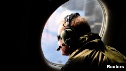 FILE - A crew member looks out an observation window aboard a Royal New Zealand Air Force (RNZAF) P3 Orion maritime search aircraft as it flies over the southern Indian Ocean looking for debris from missing Malaysian Airlines flight MH370.