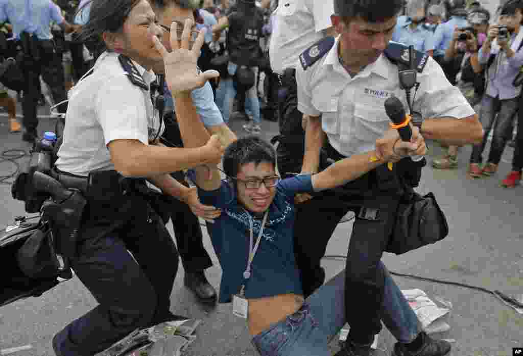 A pro-democracy protester is taken away by police officers as an ambulance tries to leave the compound of the chief executive office in Hong Kong, Oct. 3, 2014.