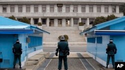 FILE - A North Korean soldier, center top, looks at South Korean soldiers at Panmunjom, March 12, 2014. Two fishermen, suspected in 16 deaths, were departed to North Korea Thursday via the border village.