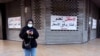 A woman walks past closed shopping center in Sidon, Lebanon, March 15, 2021. The Arabic reads: "Closed because we don't want to raise prices" and "Closed until the Lebanese Lira is rescued."