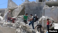 People walk on the rubble of a site hit by a barrel bomb in the rebel held area of Old Aleppo, Syria July 11, 2016. 