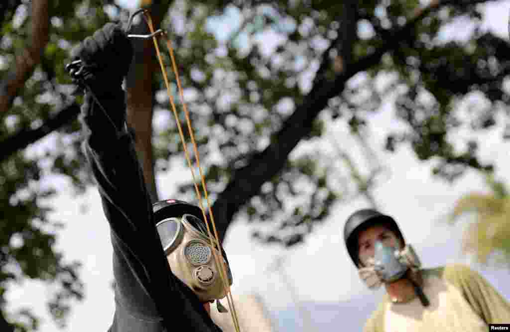 An opposition supporter uses a slingshot while clashing with security forces during a rally against the government of Venezuela's President Nicolas Maduro and to commemorate May Day in Caracas, May 1, 2019.
