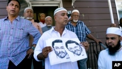 Devant l’entrée de la mosquée Al-Furqan Jame Masjid, dans le Queen, à New York, des personnes tiennent le portrait robot du présumé tueur, le 14 août 2016.