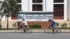 Two cyclists are seen riding past the University of Health Sciences, on 8 August 2015. (Photo: Ouch Nida/VOA Khmer)