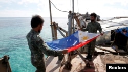 Marinir Filipina melipat bendera nasional Filipina di Second Thomas Shoal yang disengketakan, bagian dari Kepulauan Spratly di Laut Cina Selatan. (Foto: REUTERS/Erik De Castro)