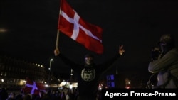 Seorang pengunjuk rasa mengibarkan bendera dalam demo menentang pembatasan terkait pandemi virus corona di Copenhagen, Denmark, 20 November 2021. 
