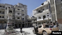 Rebel fighters inspect a site damaged by what activists said was shelling by warplanes loyal to Syria's President Bashar al-Assad in Jisr al-Shughour town, after the rebels took control of the area, April 26, 2015.