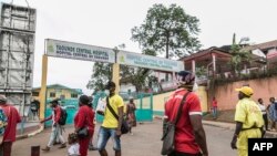 FILE - Some people wear masks as they walk by the entrance to the Yaounde General Hospital in Yaounde, March 6, 2020.