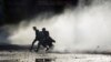 Supporters of the Tehreek-e-Labaik Pakistan (TLP) Islamist political party run to cover amid water jet during a protest against the arrest of their leader in Lahore, Pakistan, April 13, 2021.