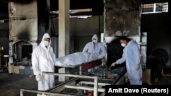 ARCHIVES : Des bénévoles se préparent à incinérer le corps d'une personne décédée de la maladie du coronavirus à Surat, en Inde, le 11 mai 2021. 