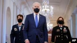 President Joe Biden walks with Air Force Gen. Jacqueline Van Ovost, left, and Army Lt. Gen. Laura Richardson before speaking at an event to mark International Women's Day, March 8, 2021, in the East Room of the White House in Washington.