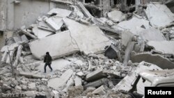 Seorang anak laki-laki berjalan di antara puing-puing reruntuhan bangunan di kota Misraba, sebelah timur kota Ghouta, Suriah, 4 Januari 2018. (Foto: dok). 