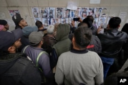 Ljudi pregledaju fotografije dok traže nestale ili umrle osobe na zidu ispred mrtvačnice bolnice Al-Mojtahed u Damasku, Sirija, 11. decembra 2024.
