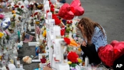 Gloria Garces kneels in front of crosses at a makeshift memorial near the scene of a mass shooting at a shopping complex, Aug. 6, 2019, in El Paso, Texas.