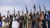A boy stands with Houthi tribesmen during a protest against a decision by the United Arab Emirates to normalize ties with Israel, in Sana'a, Yemen, Aug. 22, 2020. 