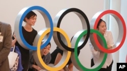 Orang-orang foto di depan logo Olimpiade di Bandara Internasional Haneda di Tokyo, Jepang, Kamis, 8 Juli 2021. (AP Photo/Koji Sasahara)