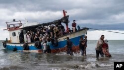 Local fisherman help ethnic Rohingya people as they arrive on Lancok Beach, North Aceh, Indonesia, June 25, 2020