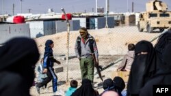 A member of Kurdish internal security stands guard at the Kurdish-run al-Hol camp, in northeastern Syria, Jan. 28, 2021.