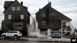 Ocean water pours off the roofs of these beachfront homes, March 6, 2018, as high surf continues in Marshfield, Massachusetts.